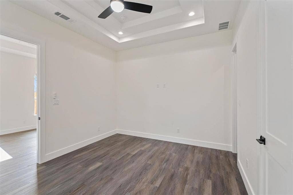 802.5 N Needmore Street, Athens, TX 75751 Empty room with a ceiling fan, dark wood-style floors, recessed lighting, and a raised ceiling