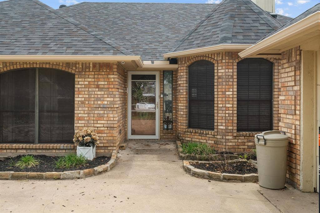 4200 Jennifer Lane, Crowley, TX 76036 View of exterior entry with a shingled roof and brick siding