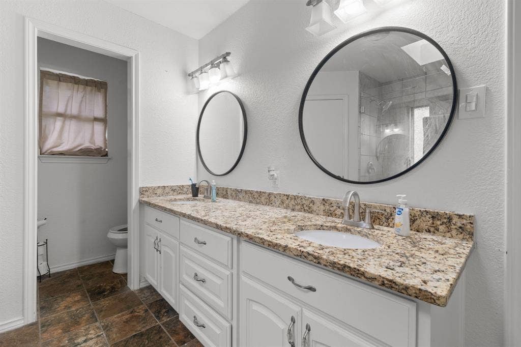 4200 Jennifer Lane, Crowley, TX 76036 Bathroom with double vanity, a textured wall, and stone finish floors
