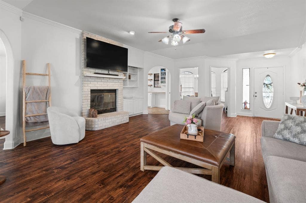 4200 Jennifer Lane, Crowley, TX 76036 Living area featuring arched walkways, crown molding, dark wood-style floors, built in features, and a fireplace