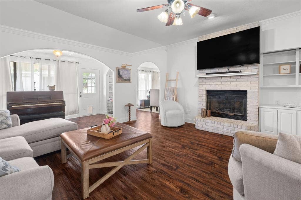 4200 Jennifer Lane, Crowley, TX 76036 Living area with a ceiling fan, a fireplace, crown molding, dark wood-style flooring, and arched walkways