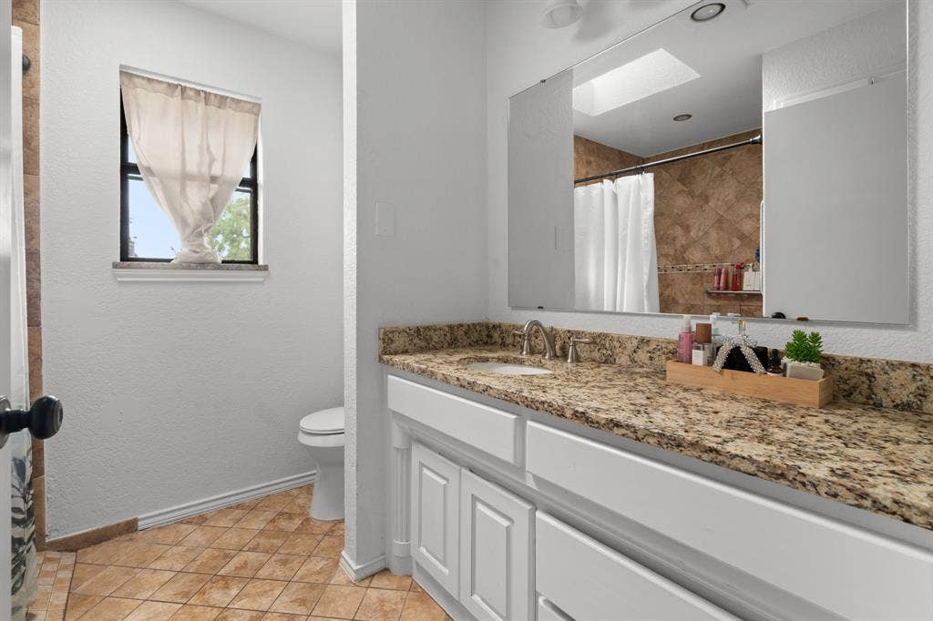 4200 Jennifer Lane, Crowley, TX 76036 Bathroom featuring vanity, curtained shower, a skylight, and light tile patterned floors