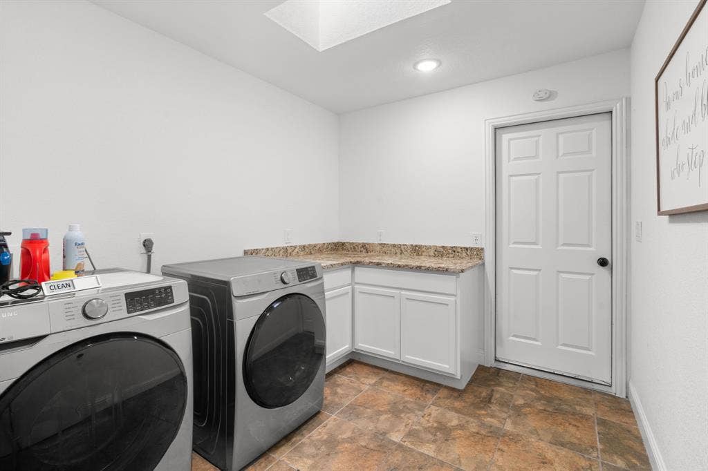 4200 Jennifer Lane, Crowley, TX 76036 Laundry area with stone finish flooring, a skylight, washing machine and clothes dryer, and cabinet space