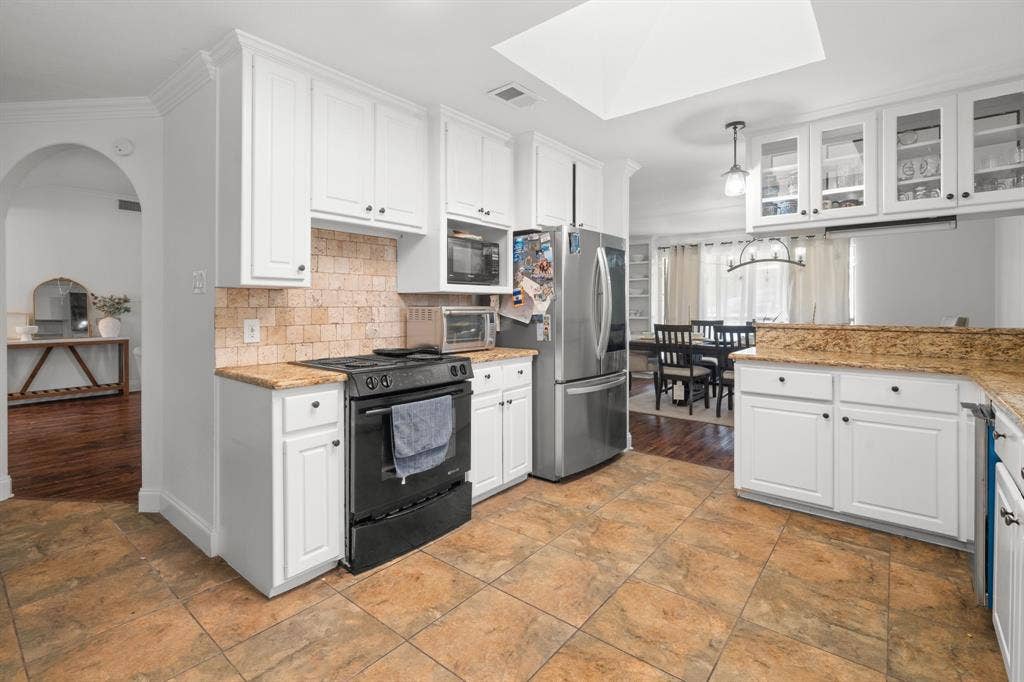 4200 Jennifer Lane, Crowley, TX 76036 Kitchen featuring white cabinetry, black appliances, light stone counters, glass fronted cabinets, and a skylight