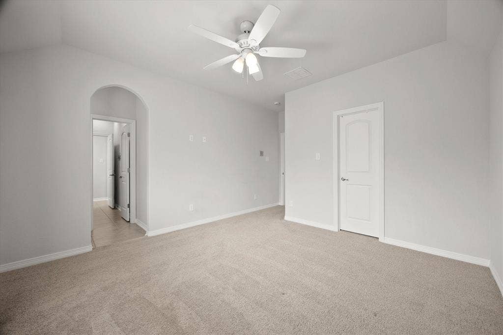 Spacious room featuring vaulted ceilings, light-colored carpeting, and a ceiling fan