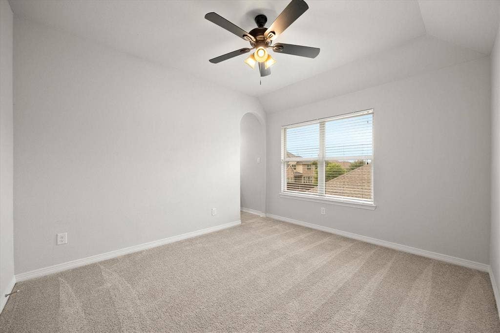 Carpeted interior space featuring a single window with horizontal blinds, a vaulted ceiling, and a ceiling fan with integrated lighting