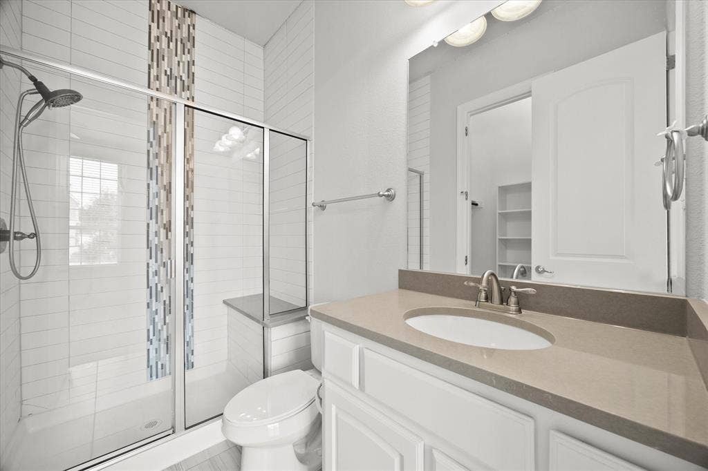 Bathroom featuring a walk-in shower with a decorative tile accent, a built-in shower bench, and a glass enclosure