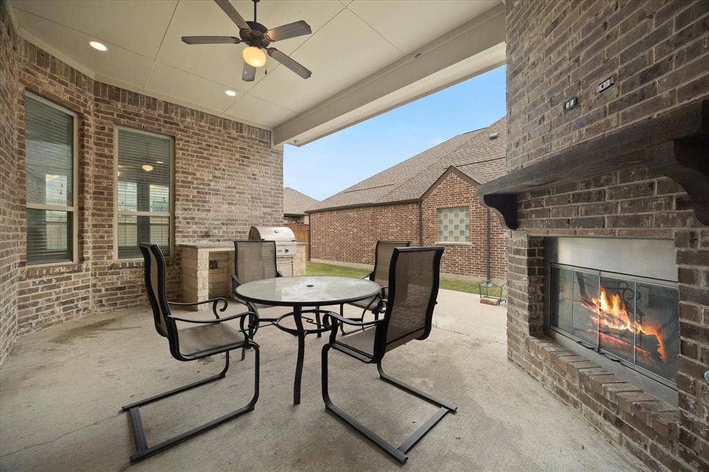 Covered outdoor patio featuring a brick fireplace with a wood mantel