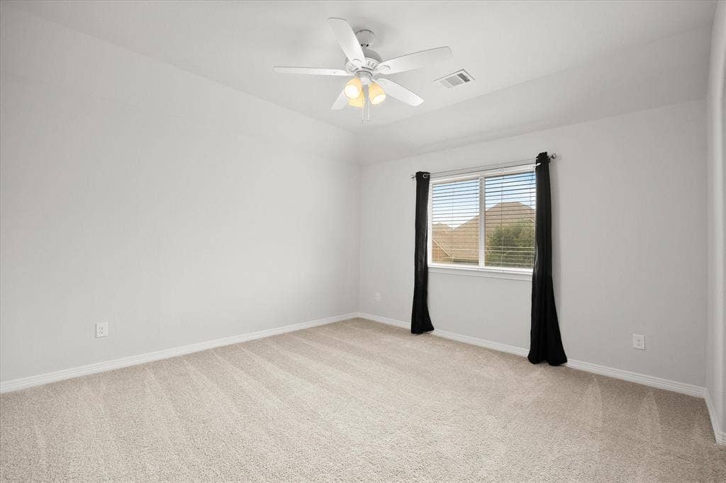 Neutral-toned carpeted room featuring a single window with blinds and a ceiling fan with integrated lighting