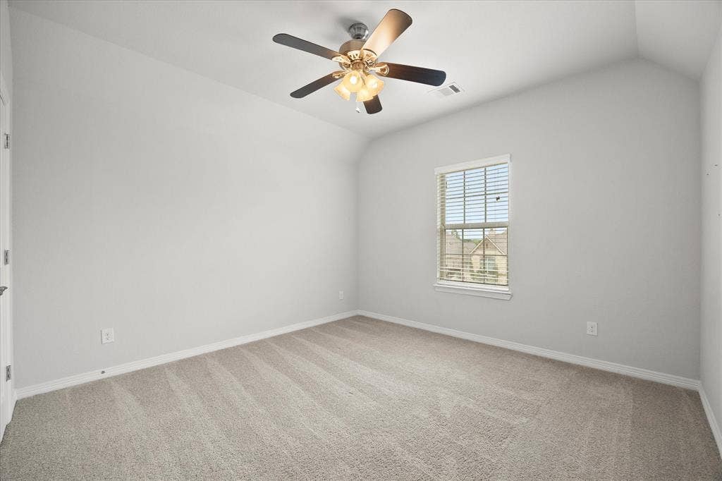 Bright interior space featuring a vaulted ceiling and a ceiling fan with light kit
