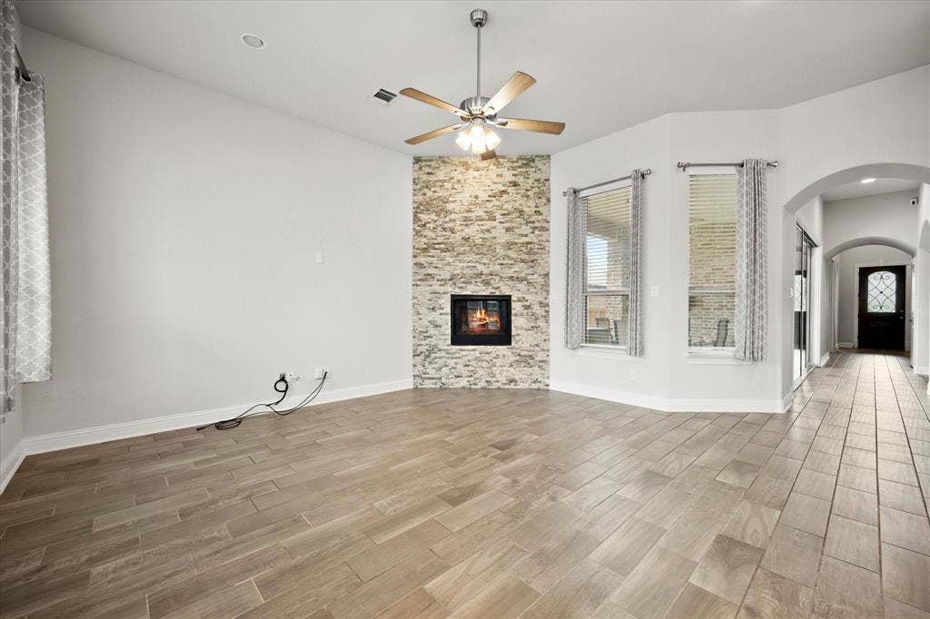 Living area featuring a floor-to-ceiling stacked stone fireplace, wood-finish flooring, a ceiling fan, and recessed lighting