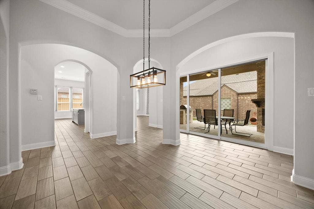 Spacious interior featuring wood-finish tile flooring, multiple arched doorways, and a modern chandelier