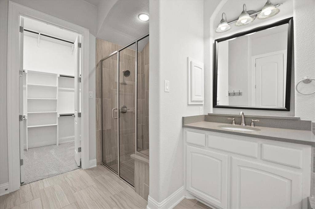Bathroom featuring a single vanity with white cabinetry, a rectangular undermount sink, and a dark framed mirror