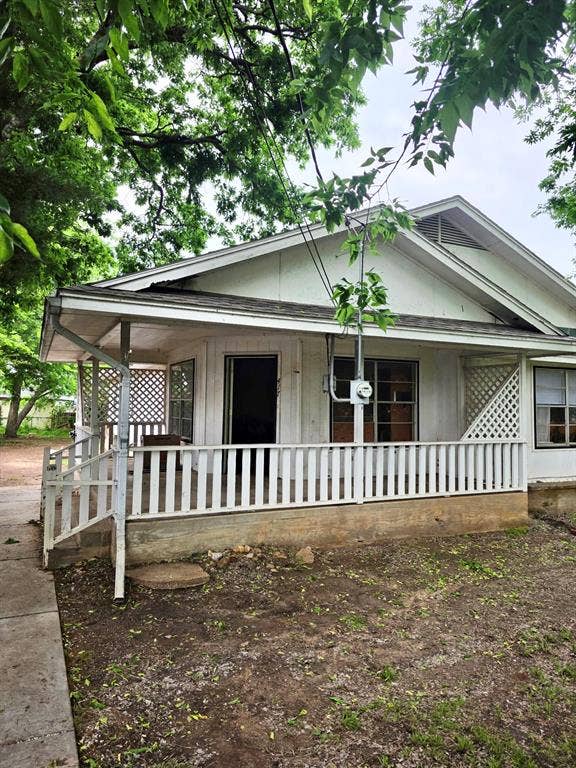 417 W Huffman Street, Krum, TX 76249 Front exterior featuring a covered porch with white railing, a gabled roofline, and lattice detailing