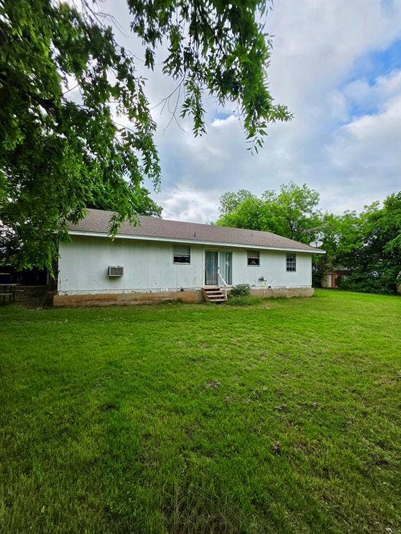 417 W Huffman Street, Krum, TX 76249 Expansive rear yard featuring a verdant lawn, mature trees, and a residential structure with white siding