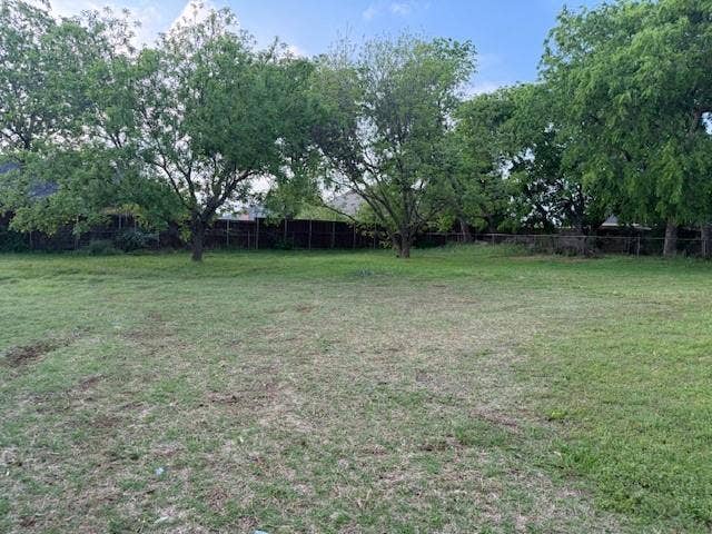 417 W Huffman Street, Krum, TX 76249 The property features an expansive lawn area with several mature trees, providing natural landscaping