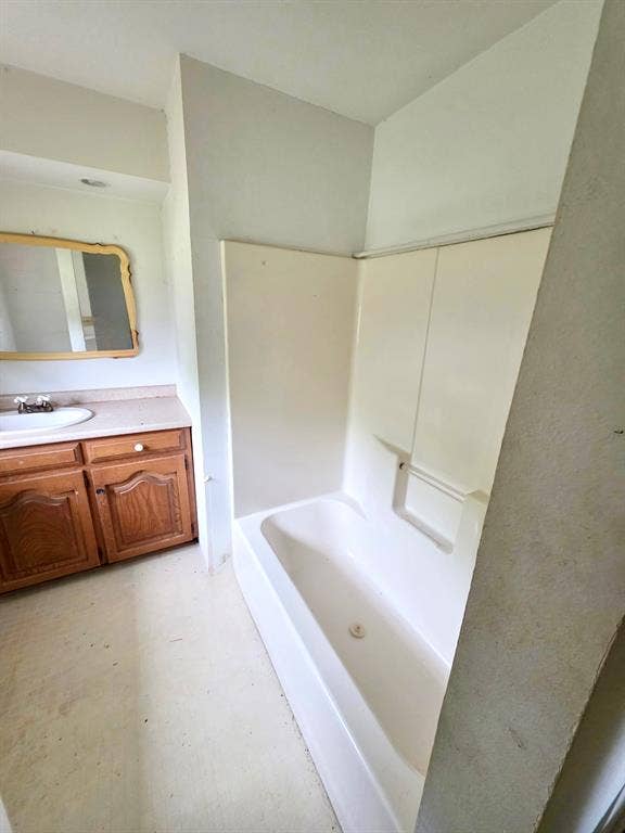 417 W Huffman Street, Krum, TX 76249 White acrylic bathtub with integrated shower surround, vanity with wood-finish cabinetry, and a countertop with an undermount sink