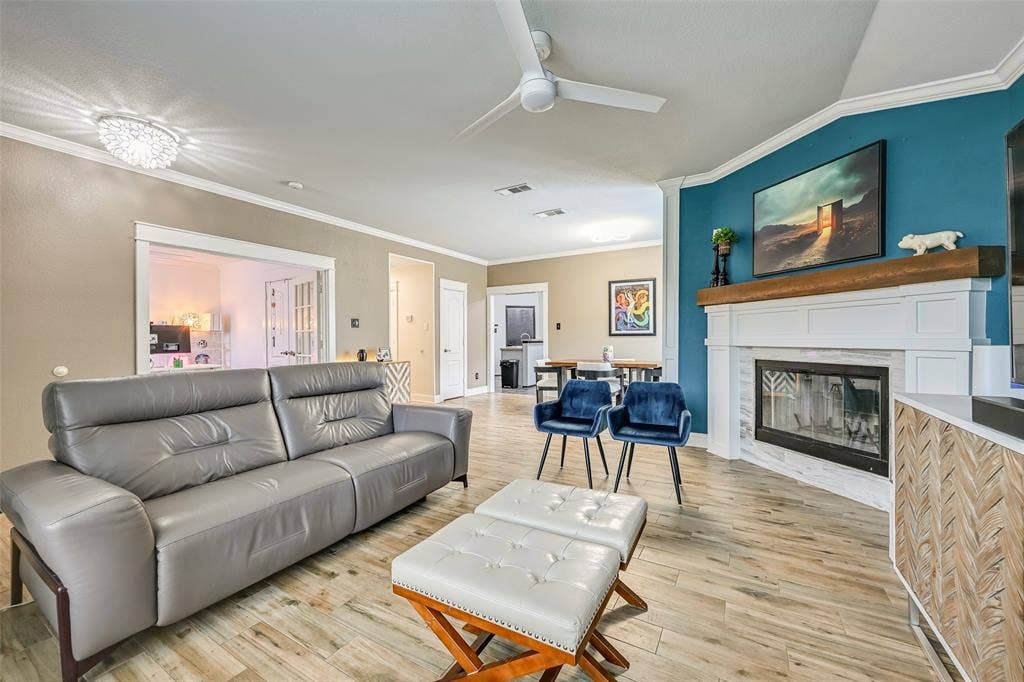 Living area featuring wood-look tile flooring, a contemporary ceiling fan, and crown molding