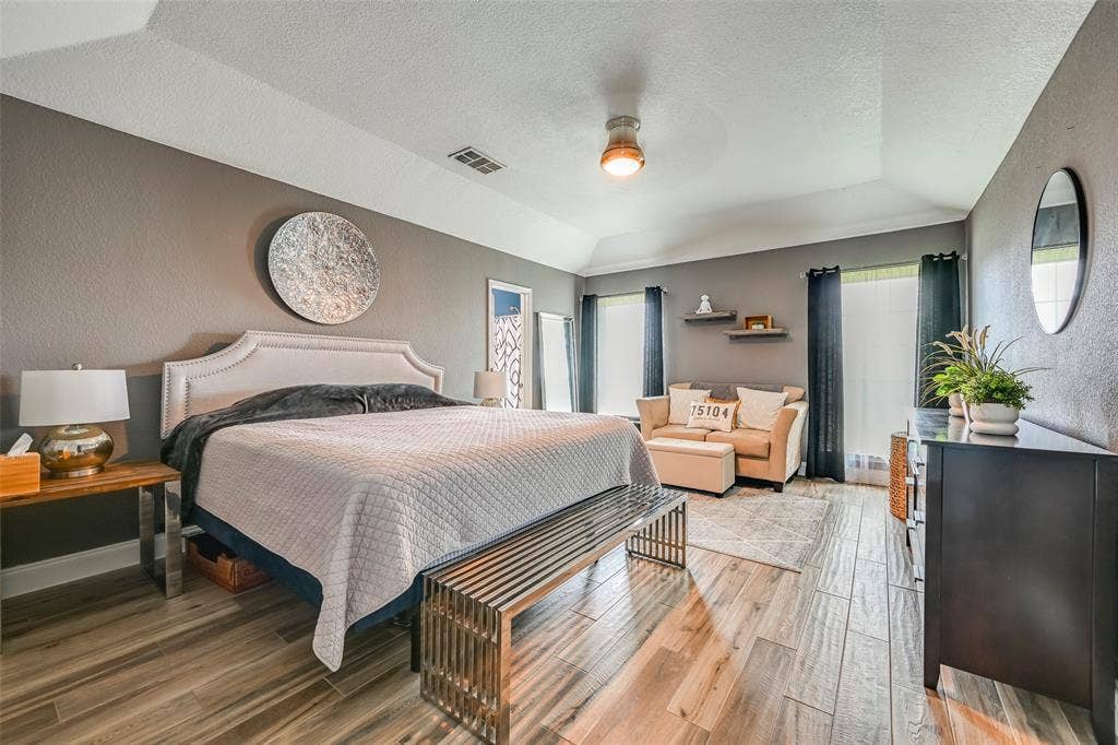 Bedroom with vaulted ceiling, neutral gray walls, and wood-look tile flooring