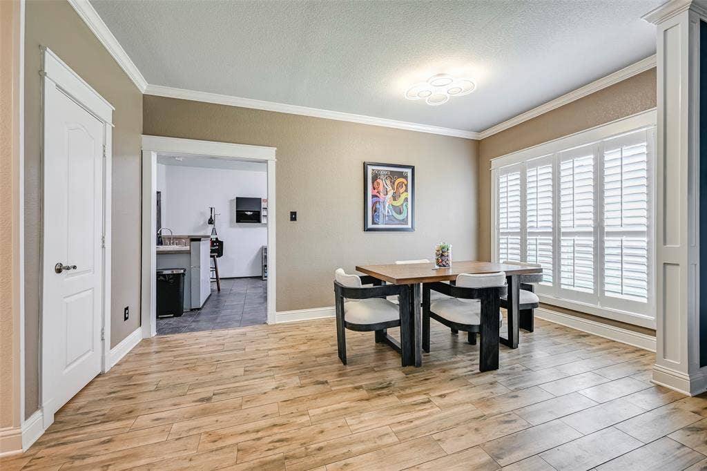 Dining area featuring wood-look tile flooring, crown molding, and a modern ceiling light fixture