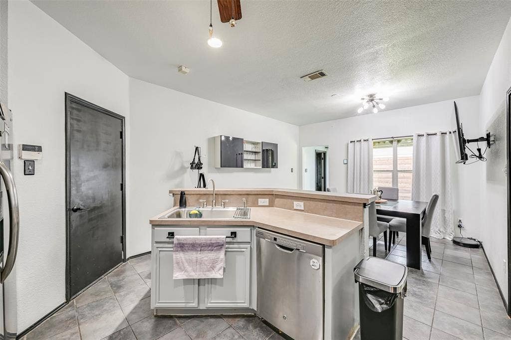 The kitchen features a stainless steel dishwasher, a double basin sink, and ample counter space