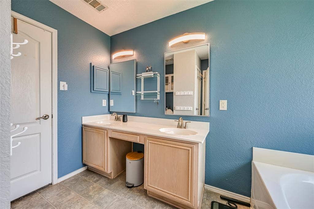 The bathroom features a double vanity with two sinks, two mirrors, and two wall-mounted light fixtures