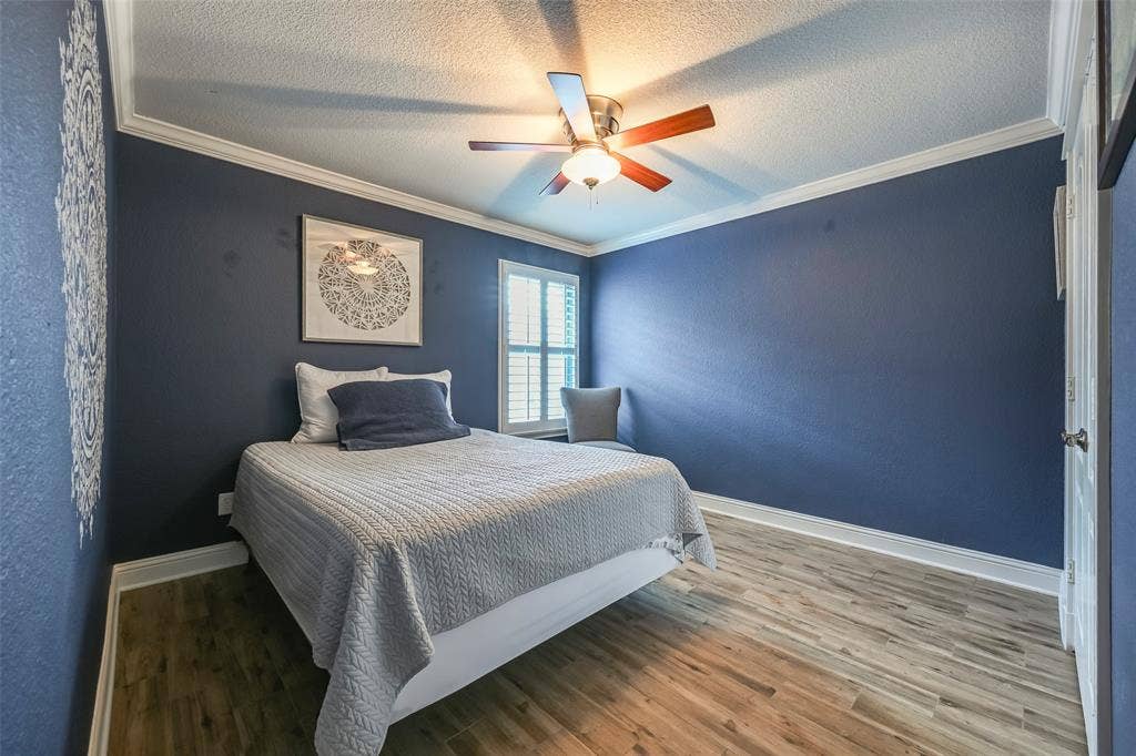 This room features wood-look flooring, crown molding, and a ceiling fan with integrated lighting
