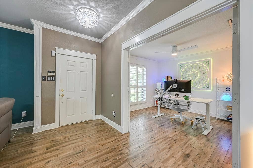 The property features wood-look flooring throughout, with crown molding and baseboards accentuating the interiors