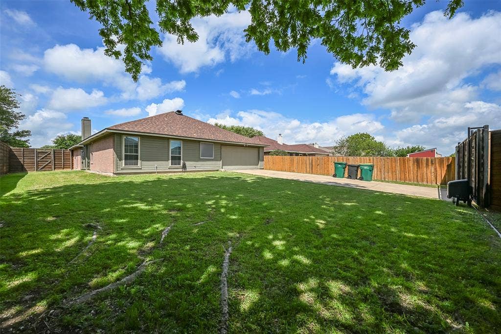 The property features a well-maintained lawn and a private wooden fence enclosing the yard