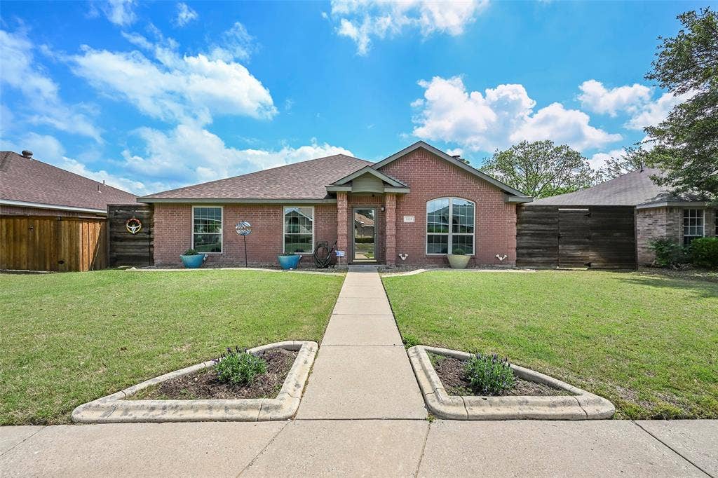 The property features a red brick exterior, a paved walkway leading to the entrance, and a well-maintained lawn