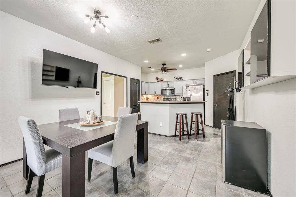 The property features an open concept kitchen and dining area with tile flooring, a breakfast bar, and a ceiling fan