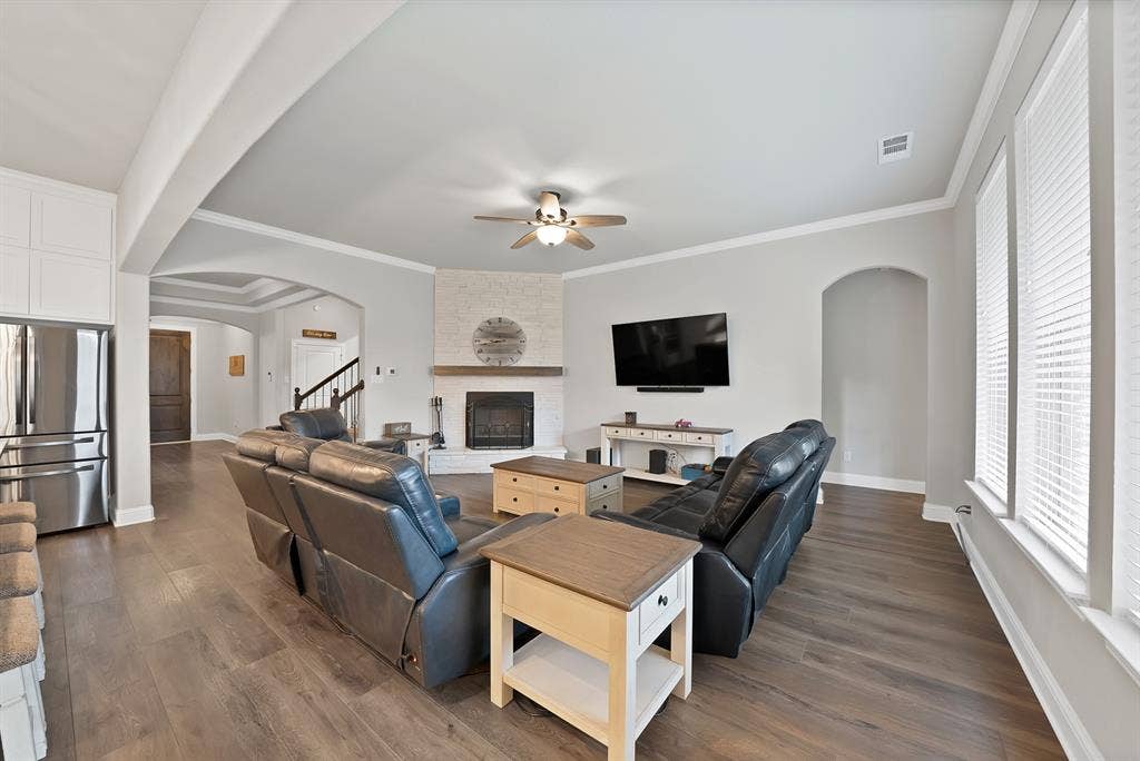 1905 Silver Falls Drive, Burleson, TX 76028 The living area features wood flooring, a fireplace with a light-colored brick surround and wooden mantel, and a ceiling fan