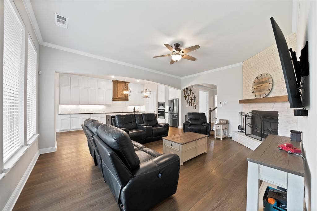 1905 Silver Falls Drive, Burleson, TX 76028 The spacious living area features hardwood flooring, a white brick fireplace with a wood mantle, and a ceiling fan
