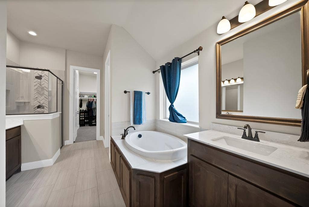 1905 Silver Falls Drive, Burleson, TX 76028 Well-appointed bathroom featuring a built-in tub, a large vanity with a rectangular sink, and a glass-enclosed shower with tiled walls
