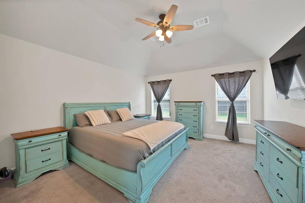 1905 Silver Falls Drive, Burleson, TX 76028 This bedroom features a vaulted ceiling with a ceiling fan, two windows with blinds, and carpeted flooring