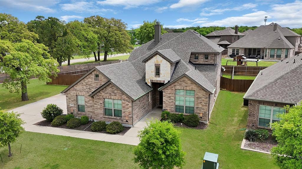 1905 Silver Falls Drive, Burleson, TX 76028 The property features a brick exterior with stone accents and a gray shingle roof