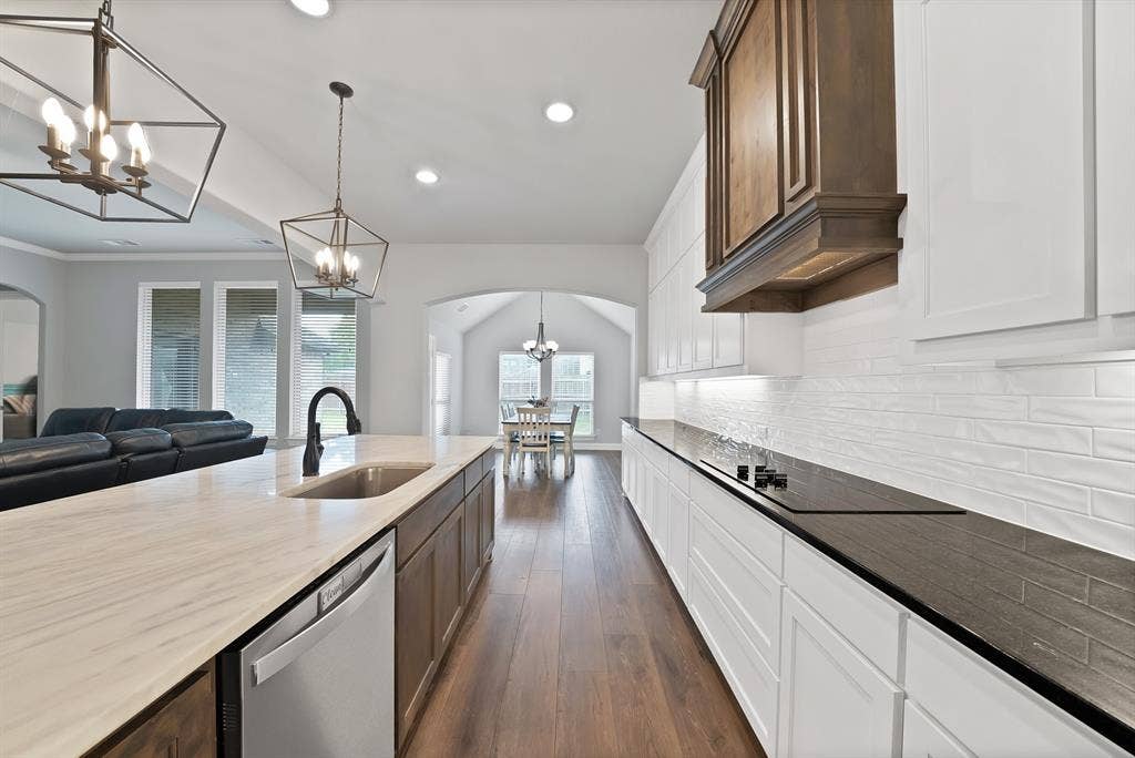 1905 Silver Falls Drive, Burleson, TX 76028 The kitchen features white cabinetry, a dark countertop, and a white subway tile backsplash, with a built-in cooktop and a range hood