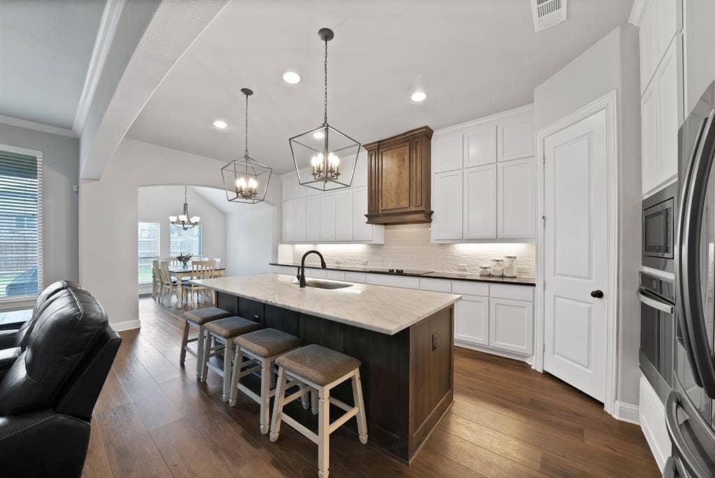1905 Silver Falls Drive, Burleson, TX 76028 The kitchen features a large island with seating, white cabinetry, dark countertops, and stainless steel appliances