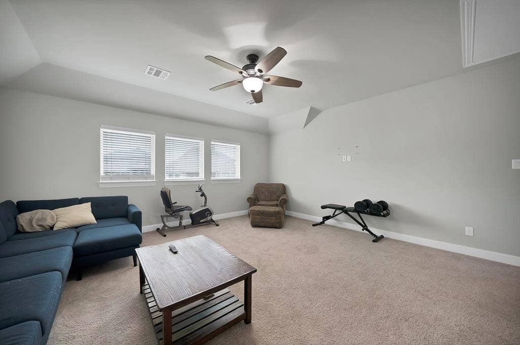 1905 Silver Falls Drive, Burleson, TX 76028 Well-lit room featuring three windows with blinds, a ceiling fan with light, and carpeted flooring