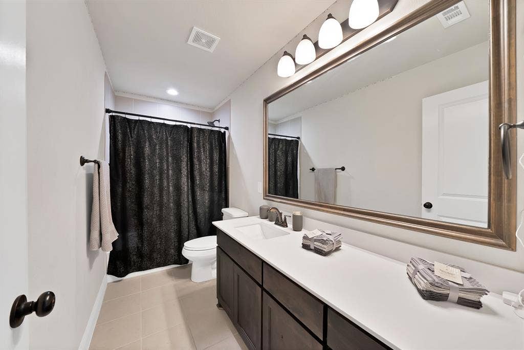 1905 Silver Falls Drive, Burleson, TX 76028 Bathroom featuring a vanity with a white countertop and dark wood cabinetry, a large mirror with a decorative frame, and overhead lighting