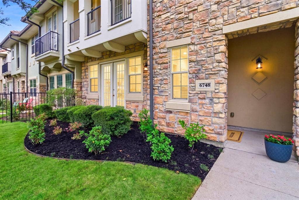 6748 San Roque, Irving, TX 75039 The property features a stone facade with contrasting trim, a well-maintained lawn, and manicured landscaping