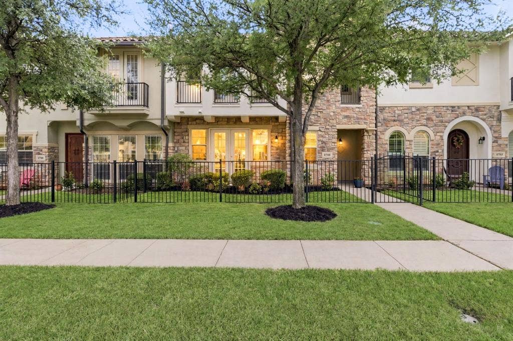 6748 San Roque, Irving, TX 75039 The property features a stone and stucco exterior, a manicured lawn with mature trees, and a paved walkway leading to the entrance