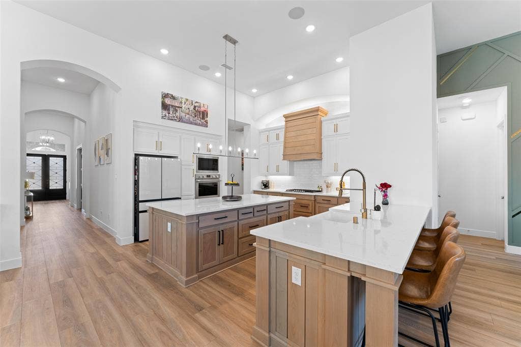 216 Shetland Lane, Northlake, TX 76247 The expansive kitchen features light wood flooring, white cabinetry, and a large kitchen island with a white countertop