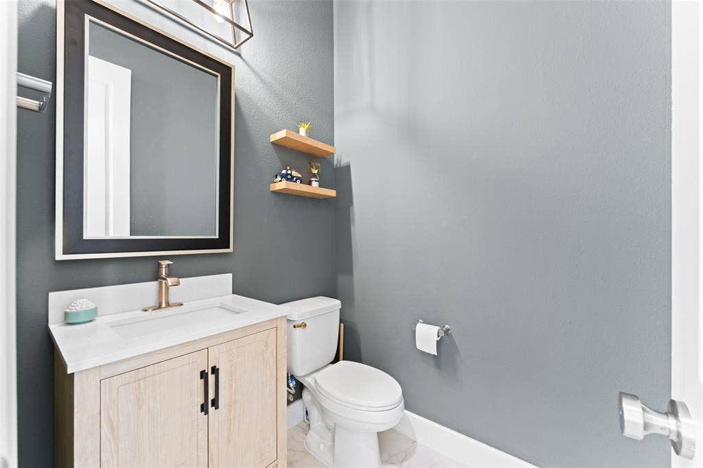 216 Shetland Lane, Northlake, TX 76247 A well-appointed powder room featuring a light wood vanity with a white countertop and a gold-toned faucet