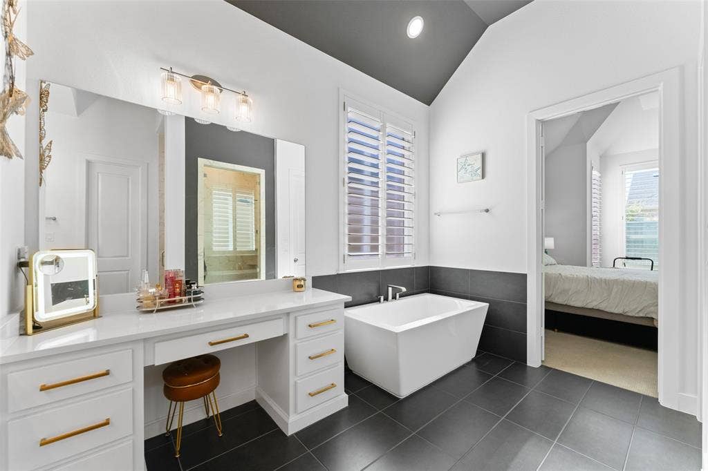 216 Shetland Lane, Northlake, TX 76247 This bathroom features a contemporary freestanding bathtub, a vanity with ample storage and a large mirror, and tiled flooring