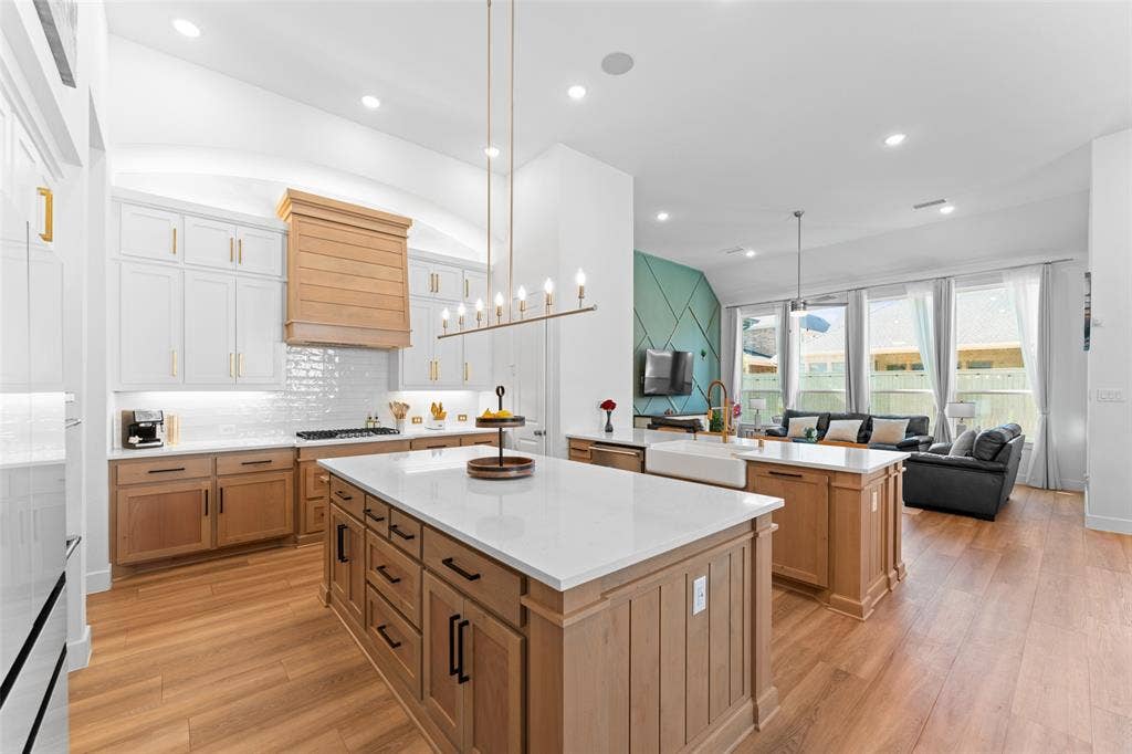 216 Shetland Lane, Northlake, TX 76247 The kitchen features a large island with a white countertop and natural wood cabinetry, a white subway tile backsplash, and a gold-toned chandelier