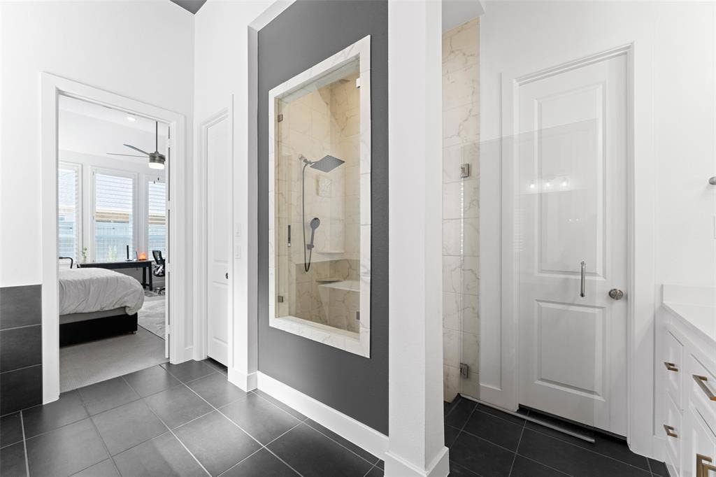 216 Shetland Lane, Northlake, TX 76247 The property features dark tile flooring, a glass-enclosed shower with a built-in bench, and white walls