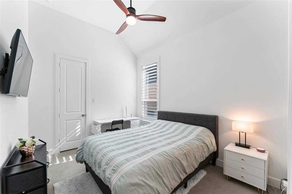 216 Shetland Lane, Northlake, TX 76247 This room features a vaulted ceiling with a ceiling fan, a window with plantation shutters, and light-colored carpeting