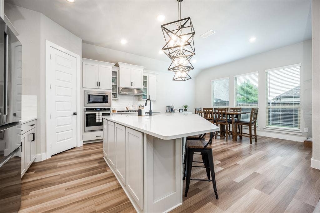 2801 Bedford Road, Northlake, TX 76226 Great modern lighting over the huge island. The white cabinets complement the floors perfectly.