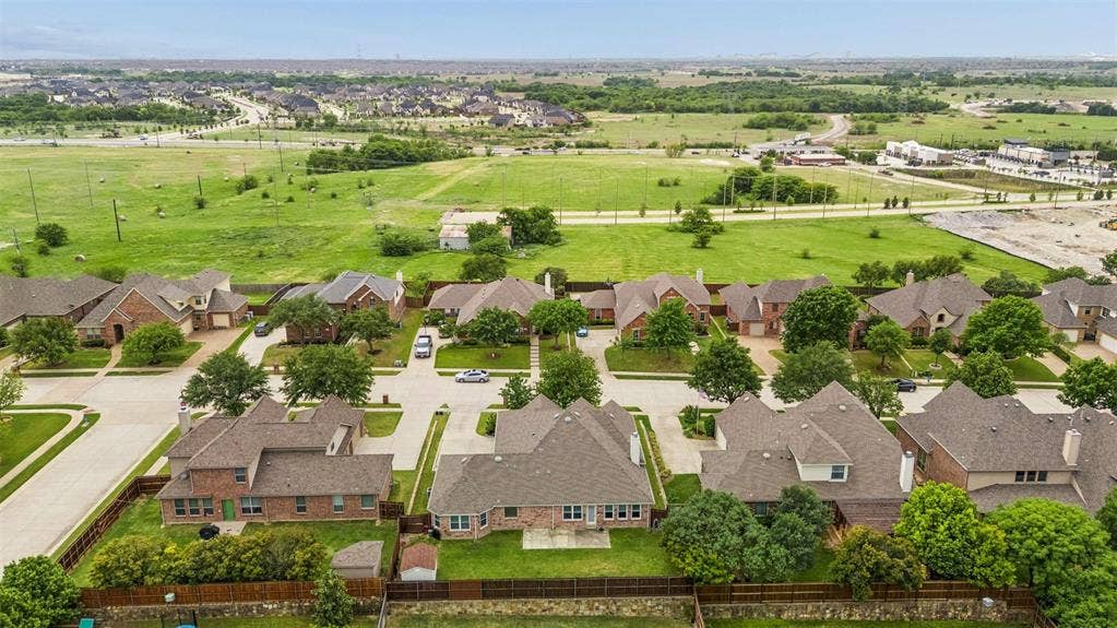 1221 Amistad Drive, Prosper, TX 75078 An aerial view showcases the property within a neighborhood setting, featuring residential streets, green spaces, and surrounding developments
